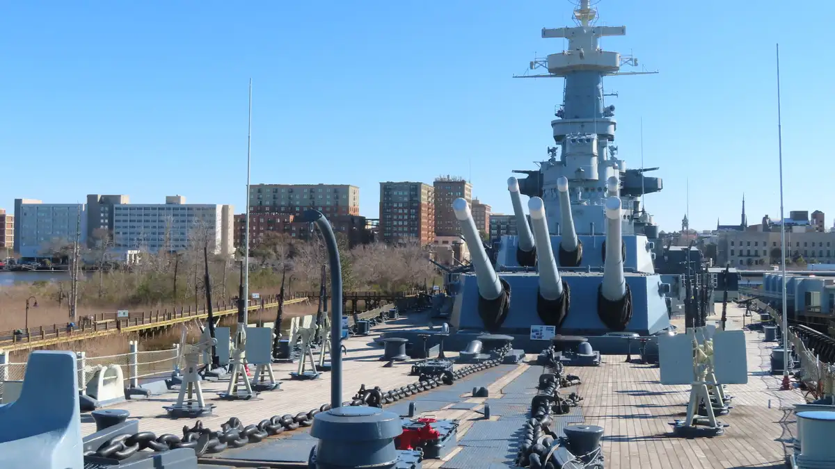 The forward guns of the USS North Carolina, with the Wilmington skyline behind