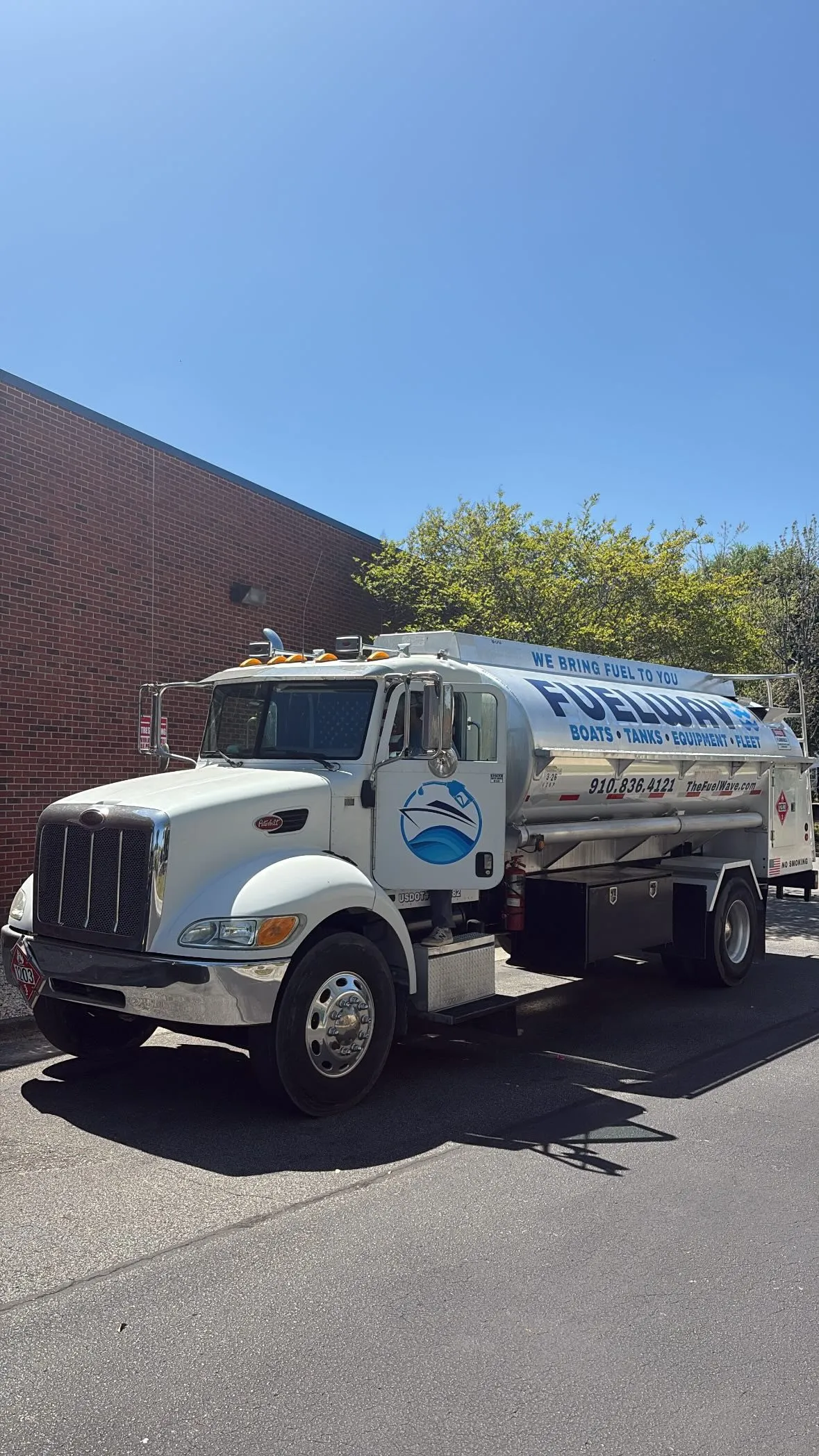 The Fuel Wave tanker parked beside a brick building, wordmark and phone number along the tank