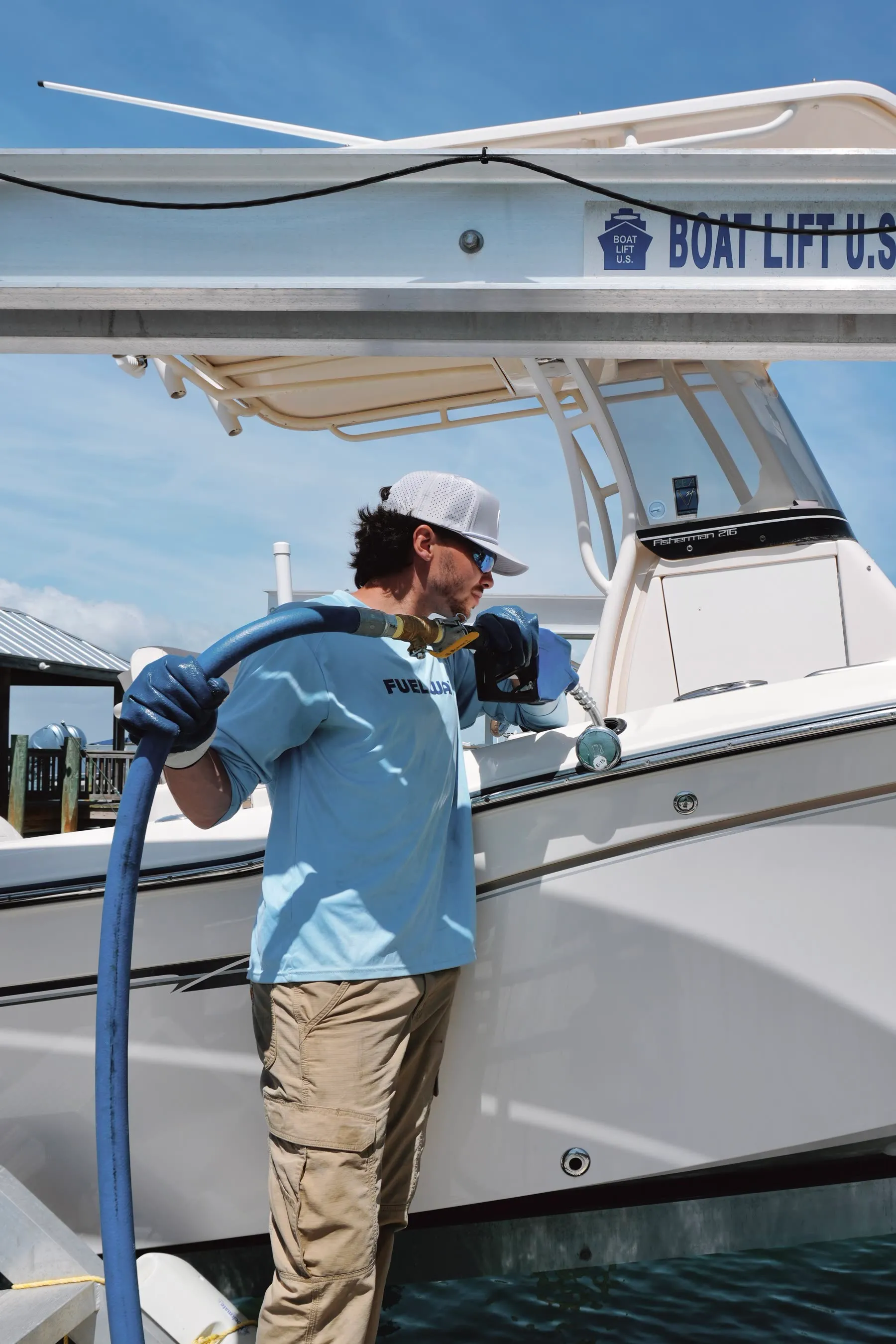 A Fuel Wave team member carrying the fuel hose to a center console at the dock
