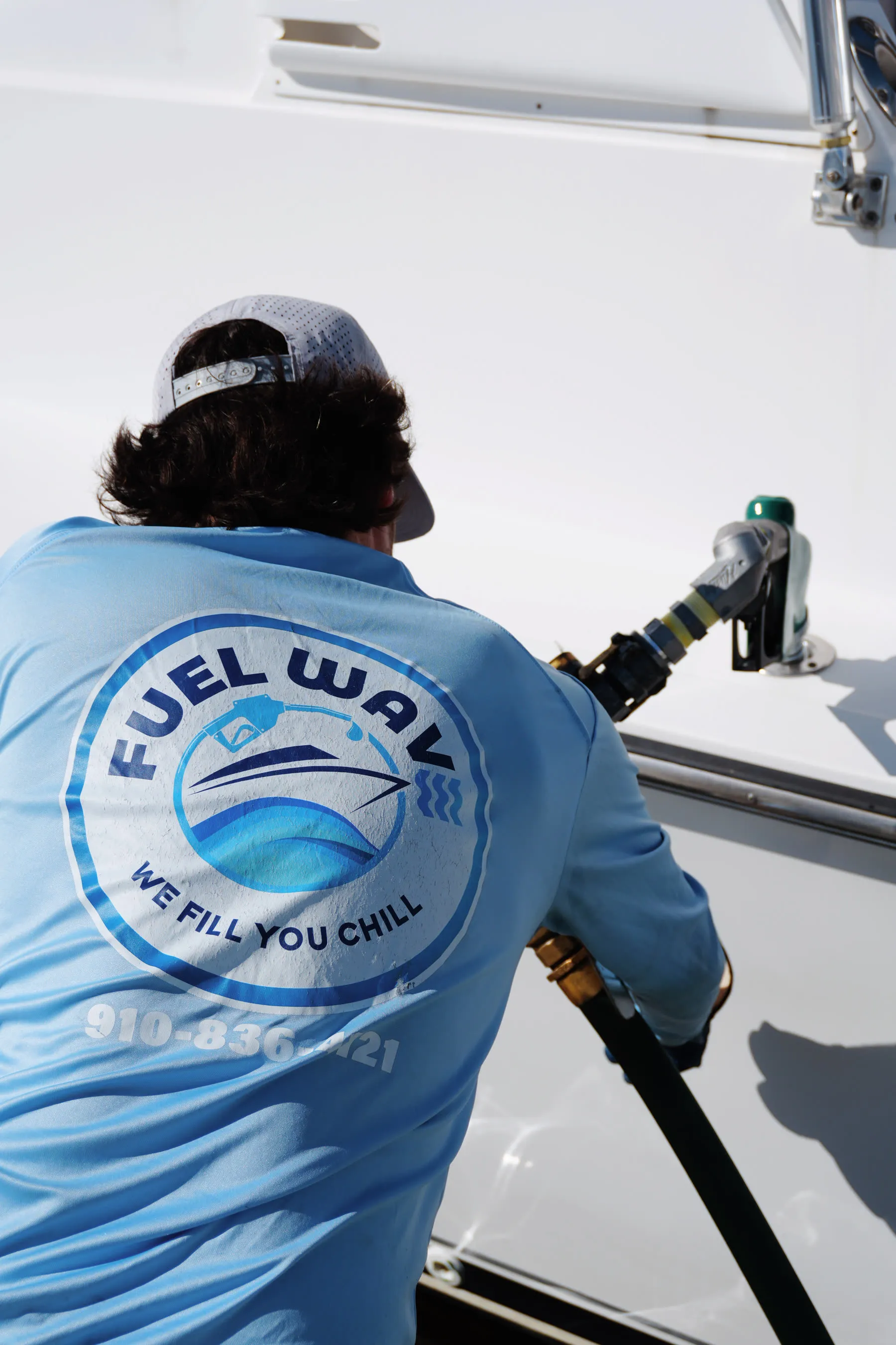 A Fuel Wave crew member carrying the hose down the dock to a customer's boat