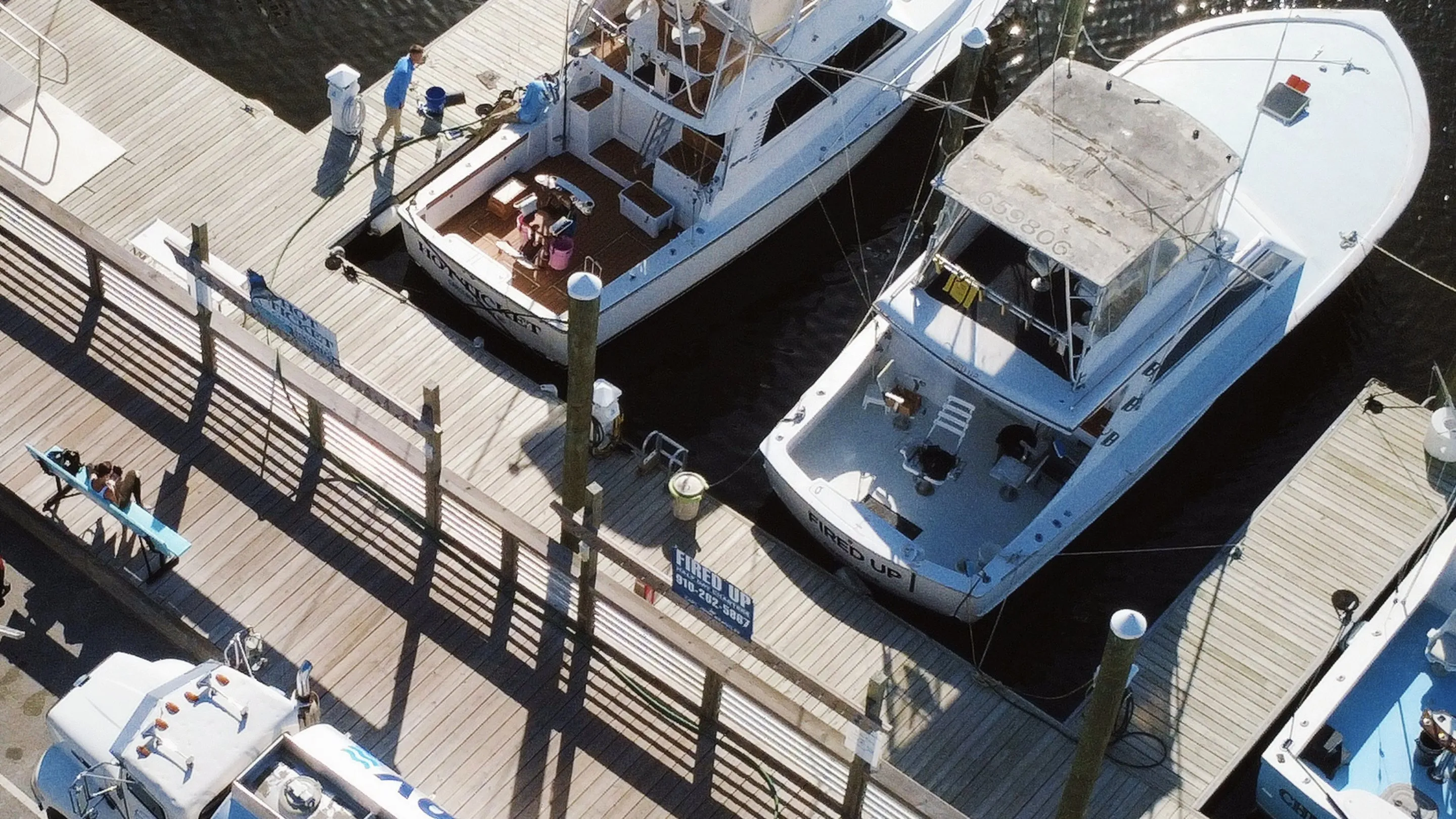 Sportfishing boats moored either side of a marina dock, seen from above