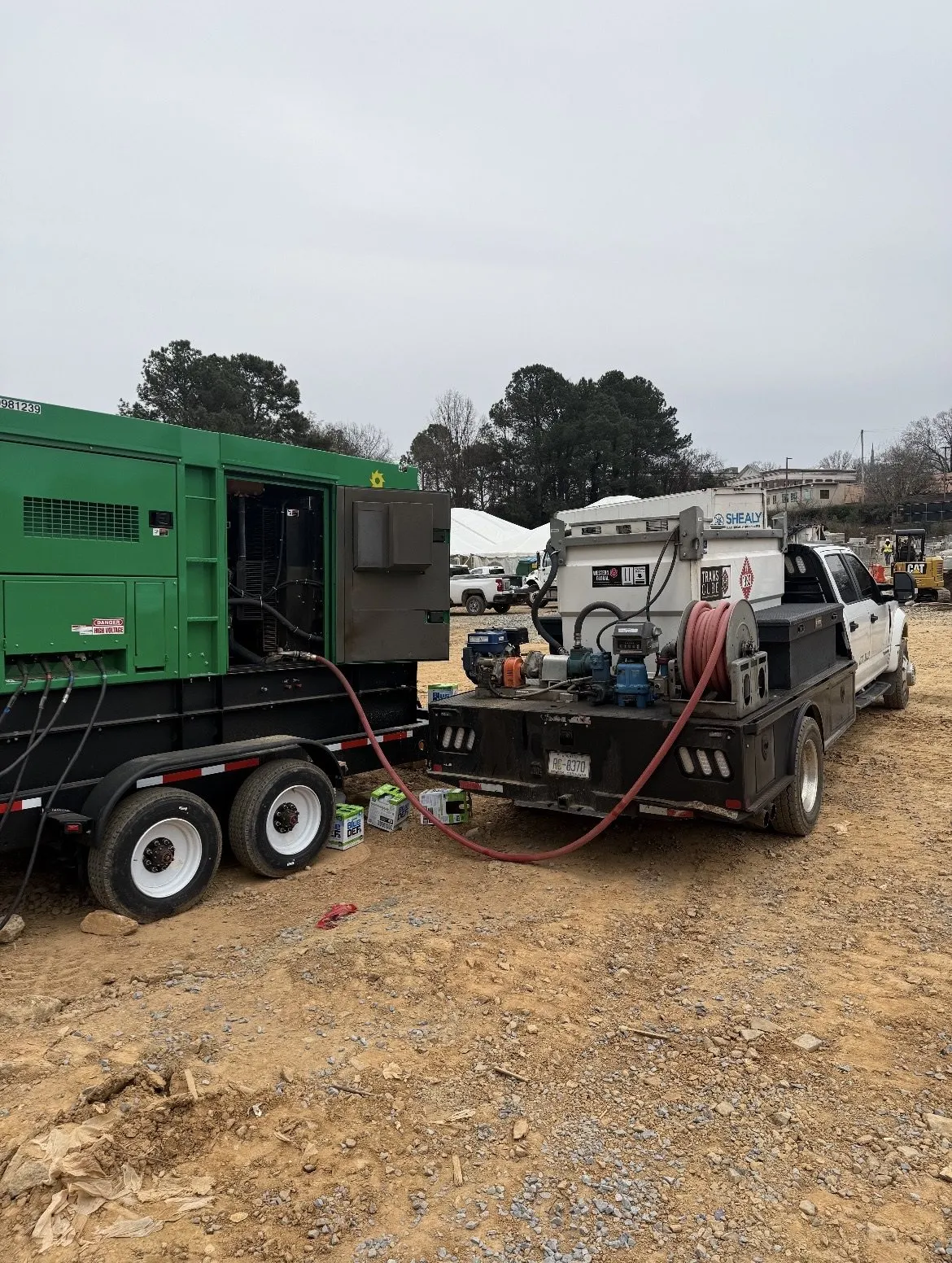 The Fuel Wave flatbed fueling a green towable generator on a job site, hose run from the reel