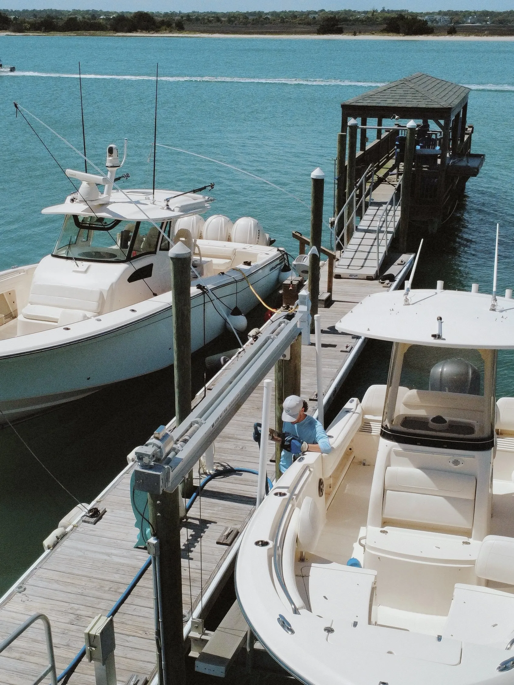 A crew member on the dock fueling a center console, a second boat in the next slip, seen from above